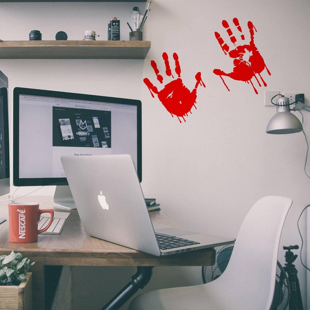 Spooky red handprint vinyl decals on a wall near a laptop in a modern workspace.