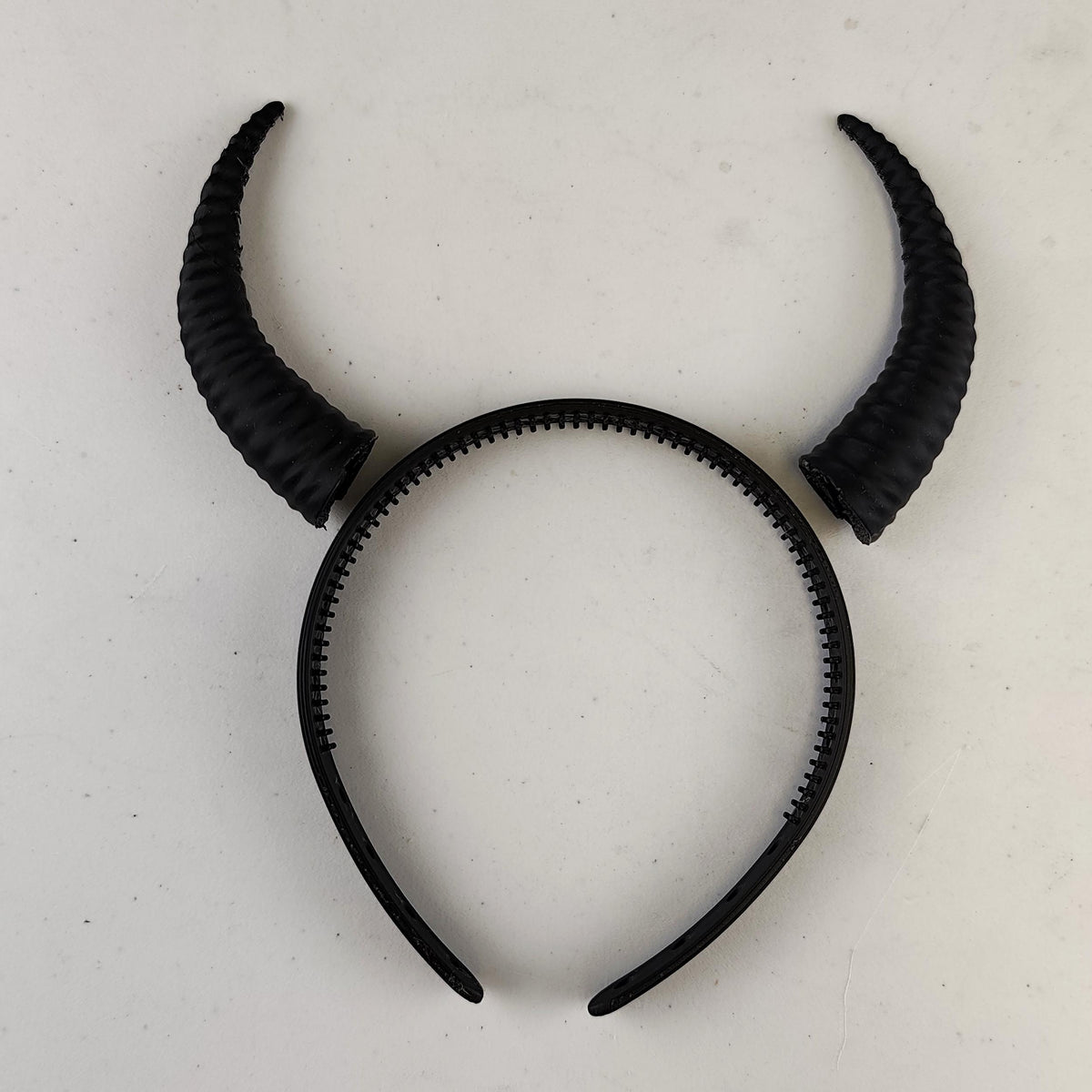 Physical subtle curved demon horns headband designed with a coordinated pair of textured curved horns mounted on a lightweight band