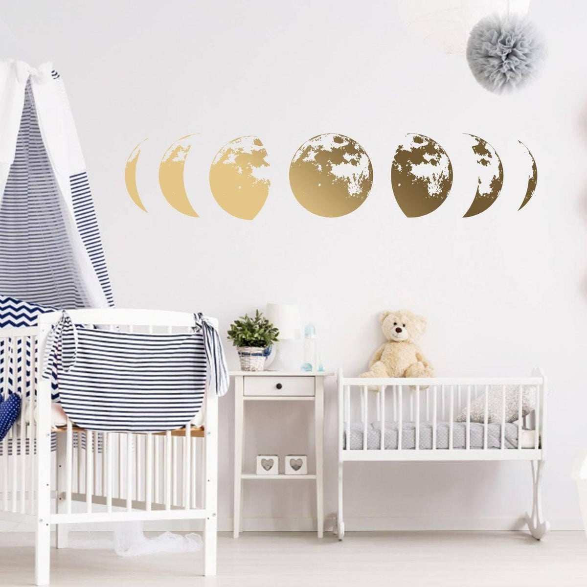 Gold moon phases wall decal above a crib, adding a moon-themed decor touch to a nursery.