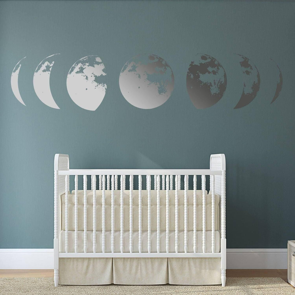 Moon phases wall decal above a white crib, adding a serene touch to a nursery with a blue wall.