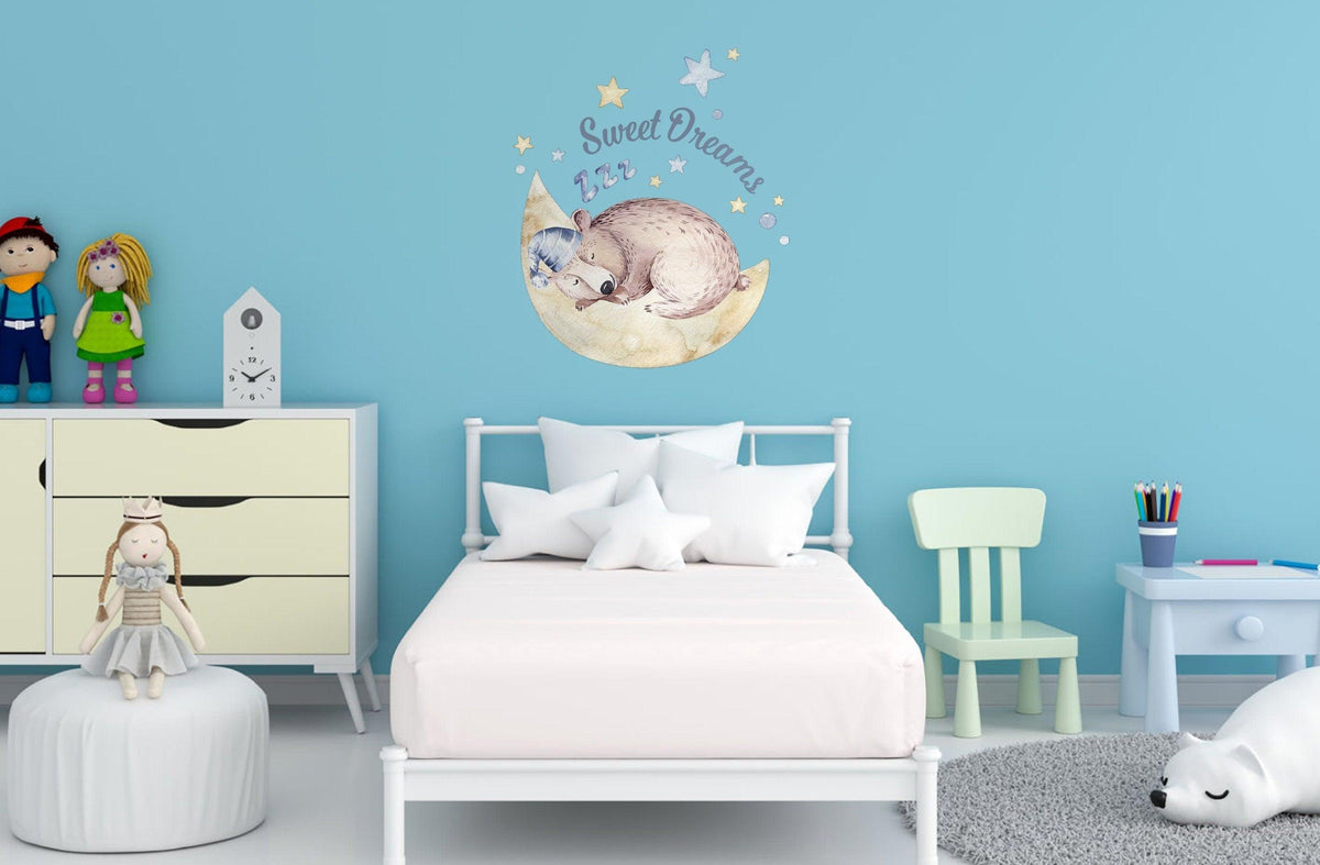 Nursery wall with 'Sweet Dreams' decal featuring a sleeping animal on a moon, colorful kids' decor in a bright blue room.