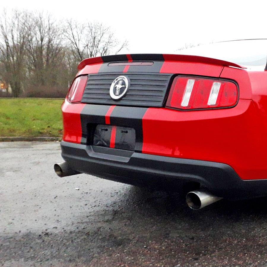 Red car with stylish black racing stripes on the back, showcasing a sporty and upgraded look.