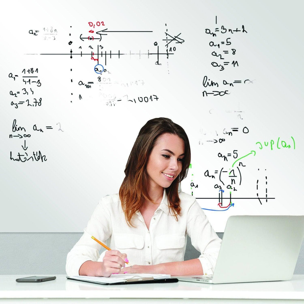 Woman studying with notes on a dry erase whiteboard, using a laptop and writing with a marker.