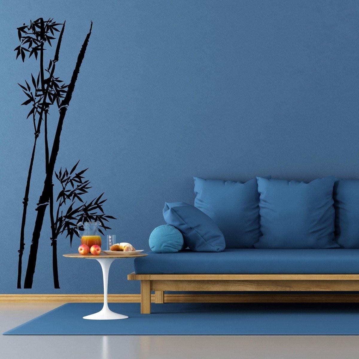 Bamboo wall art decal on blue wall in a modern living room with a cozy couch and decorative table.