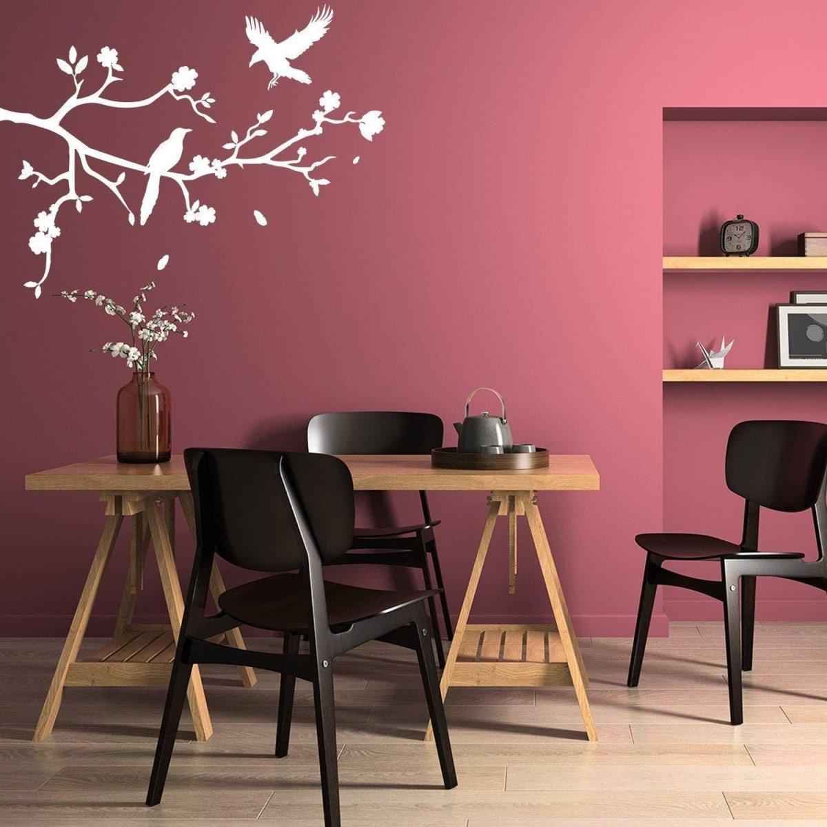 Chic tree branch wall decal featuring birds, adding stylish decor to a dining room with pink walls.