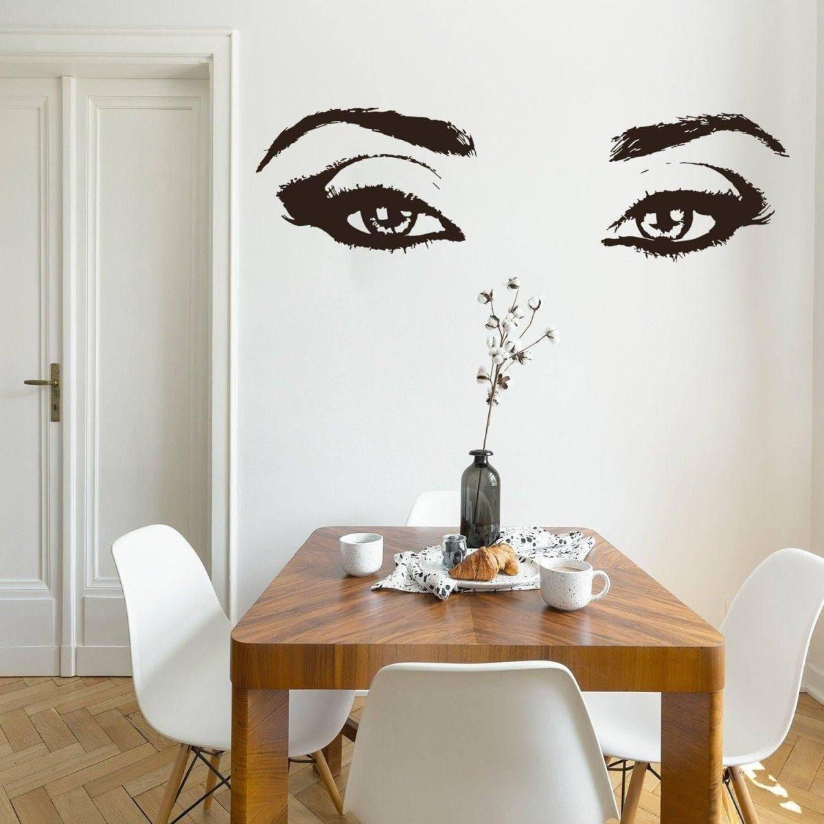 Elegant vinyl wall decal of a woman's eyes above a wooden dining table, enhancing room decor with style.