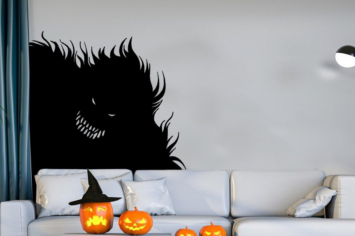 Spooky monster silhouette wall decal above Halloween pumpkins in a cozy living room setting.