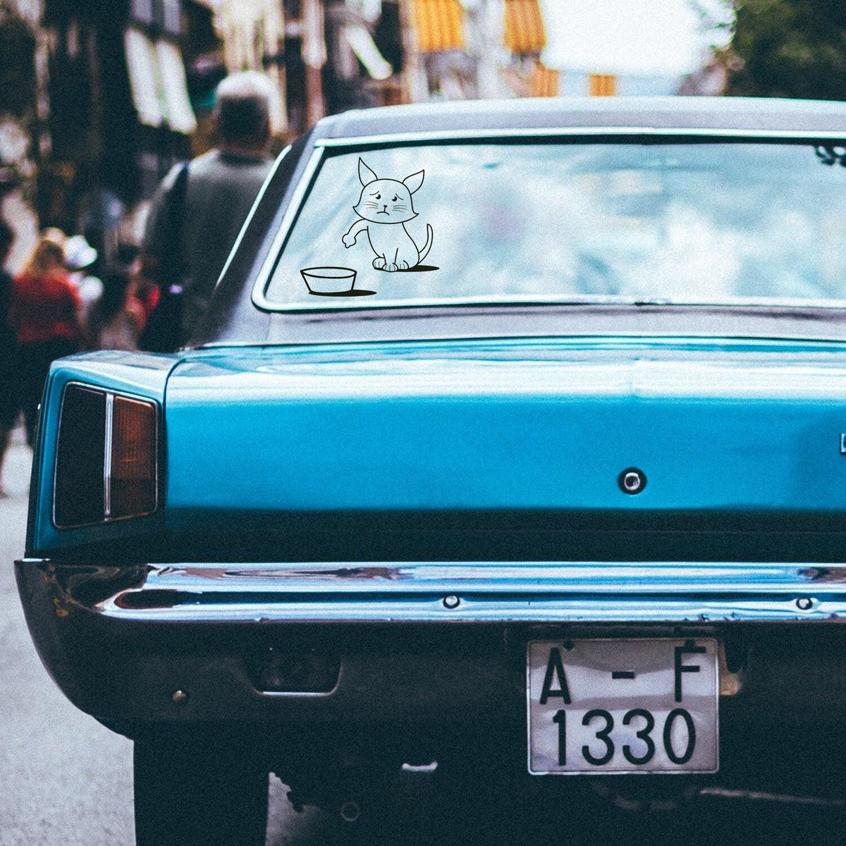Funny cat vinyl sticker on a blue car's rear window, reminding to fill gasoline tank.
