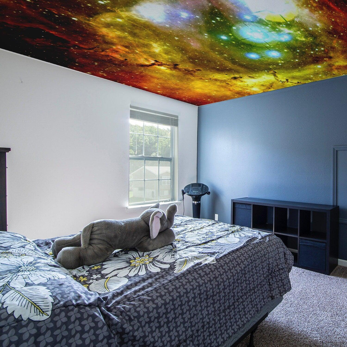 Space theme ceiling vinyl sticker in bedroom, featuring colorful galaxy design with stars and planets.