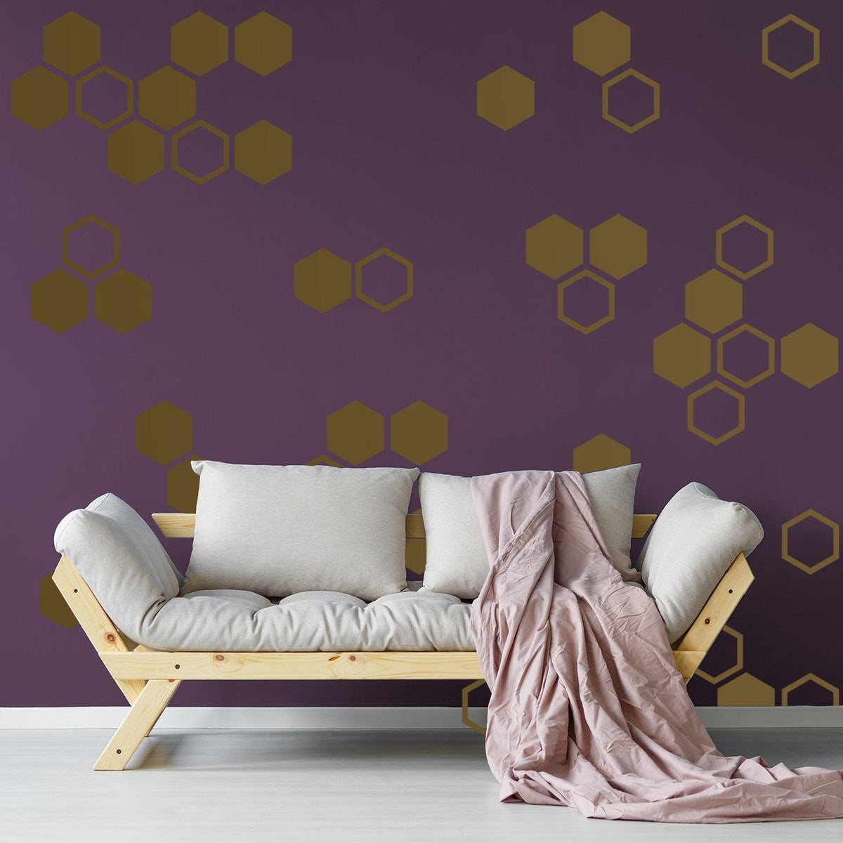 Honeycomb wall decals in geometric hexagon design on a purple wall above a cozy couch with blankets.