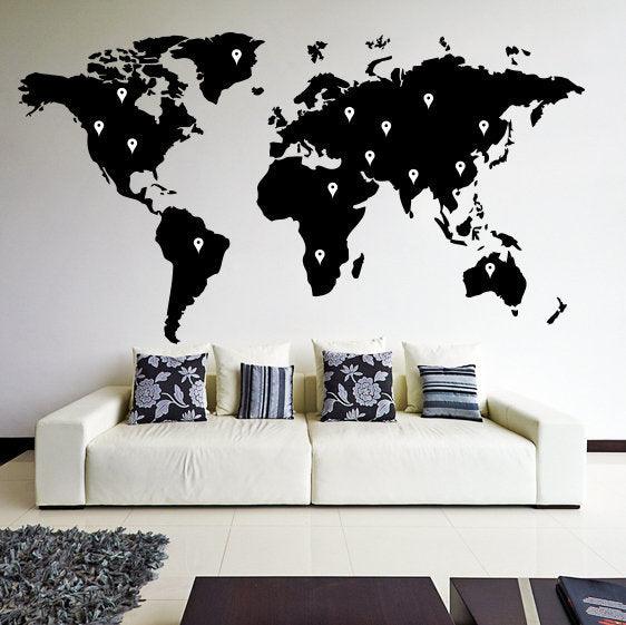 Large black world map wall decal design on a living room wall above a white sofa with decorative pillows.