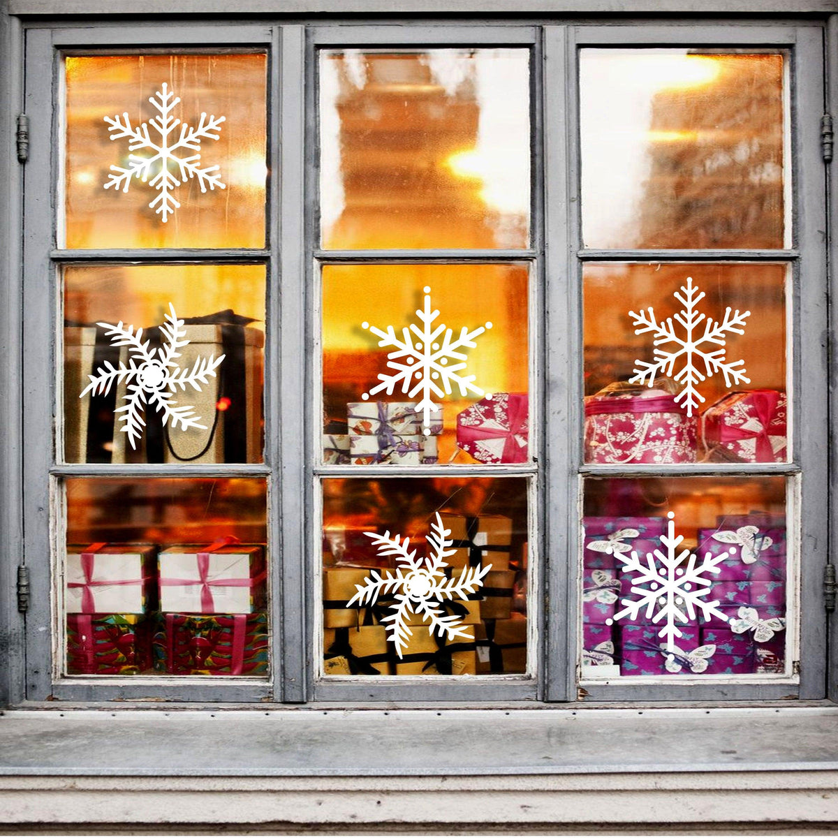 100x Christmas snowflake window stickers decorating a cozy shop window with gift boxes.
