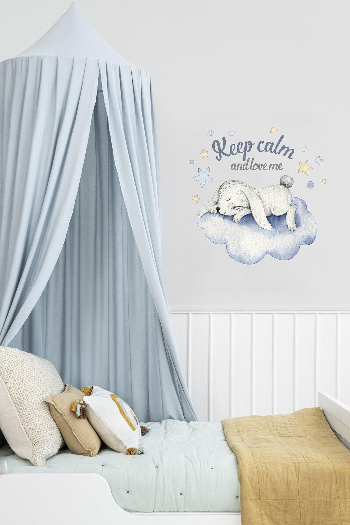 Baby nursery decor with a cozy cloud design, featuring a sleeping animal and a calming message above a bed.