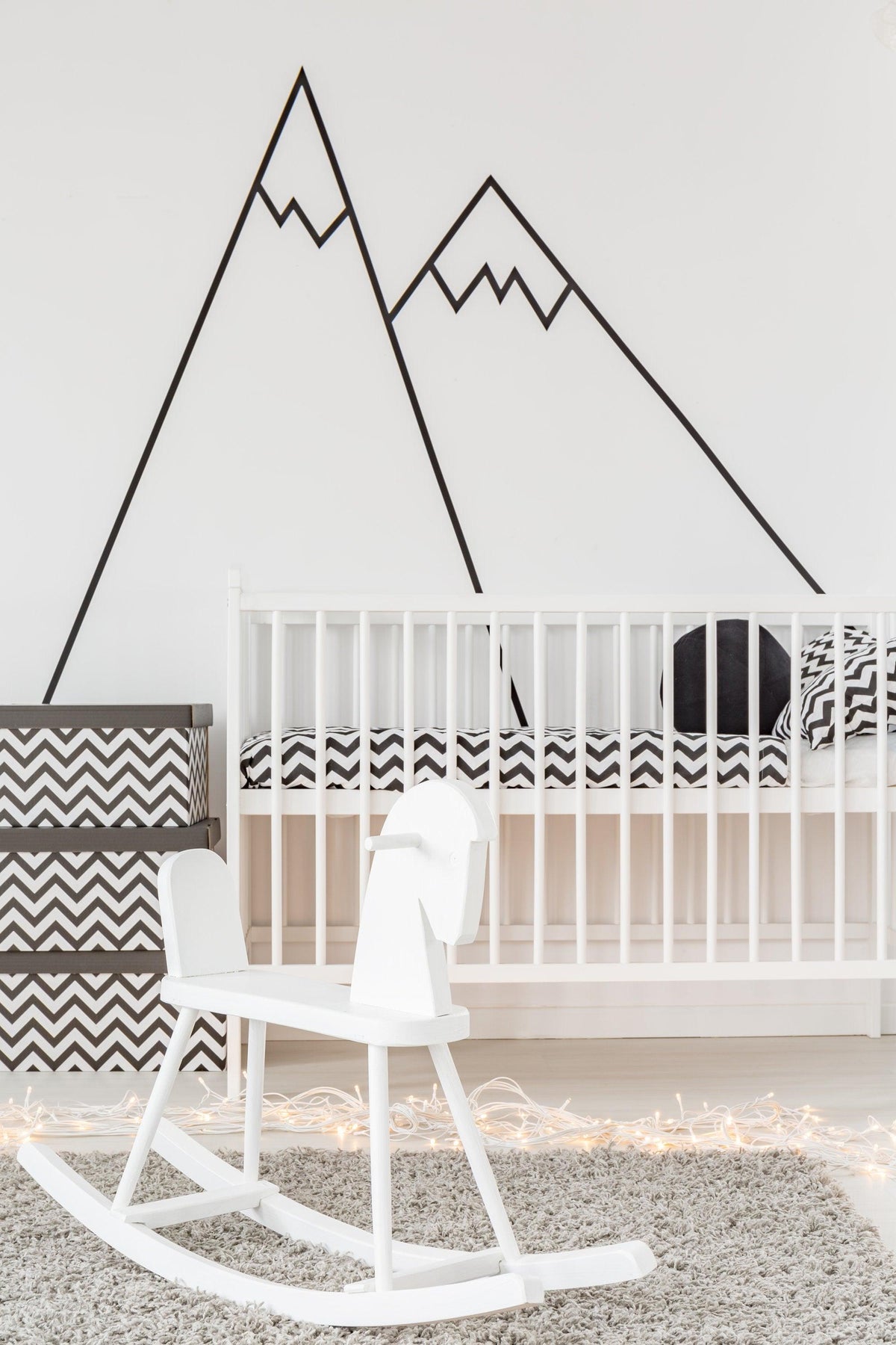 Black mountain peel and stick decals above a white crib in a cozy nursery setting, featuring modern decor elements.