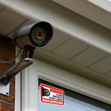 Video surveillance camera with warning sign posted on window for enhanced home security.