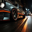 Close-up of a stylish car with orange geometric peel-and-stick decals parked on a city street at night.