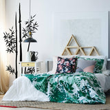 Bamboo wall vinyl decal in a modern bedroom with green bedding and floral pillows, enhancing natural decor.