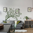 Abstract tree branch wall sticker as indoor decor in modern living room with plants and framed artwork.