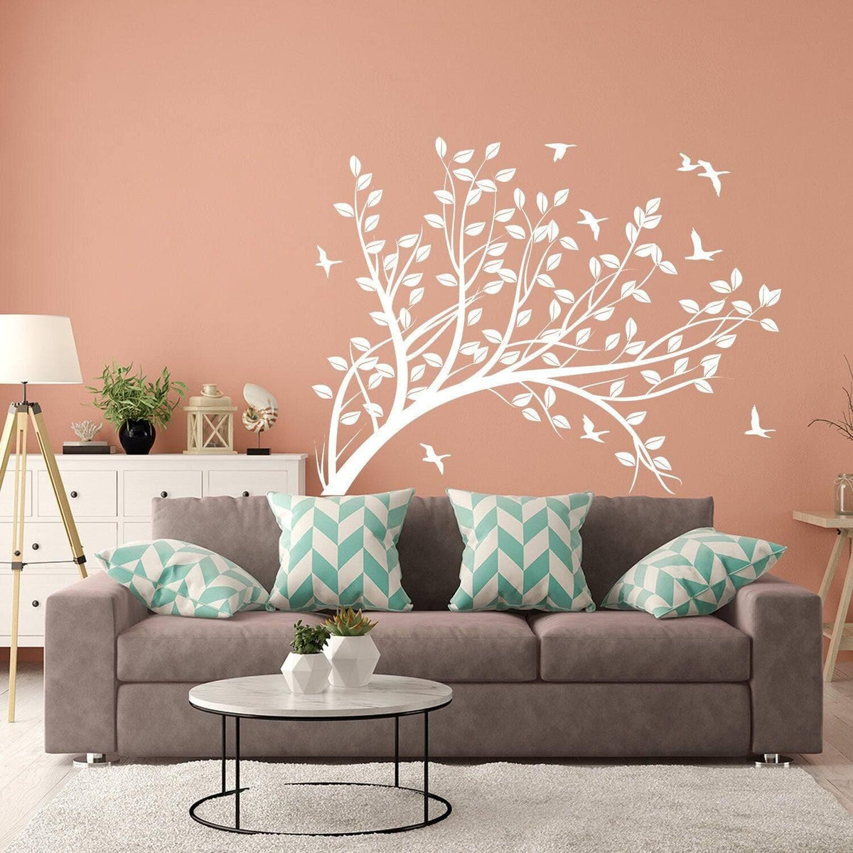 Abstract tree branch wall sticker in a cozy living room with teal pillows and warm peach walls.