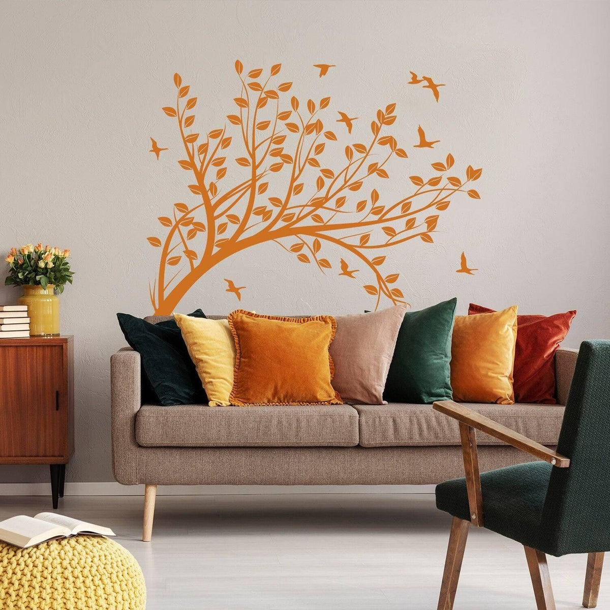 Abstract tree branch wall sticker in orange, adding artistic charm to a cozy living room with colorful cushions.