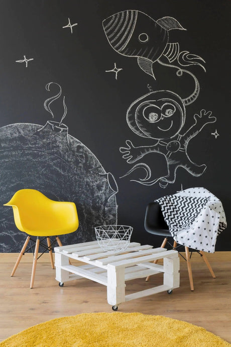 Creative chalkboard wall with astronaut and rocket drawings, featuring stylish furniture and vibrant decor.