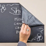 Person peeling back a chalkboard wall decal with a shopping list written on it, showcasing its creative versatility.