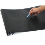 Person drawing with blue chalk on a smooth black chalkboard wall sticker.