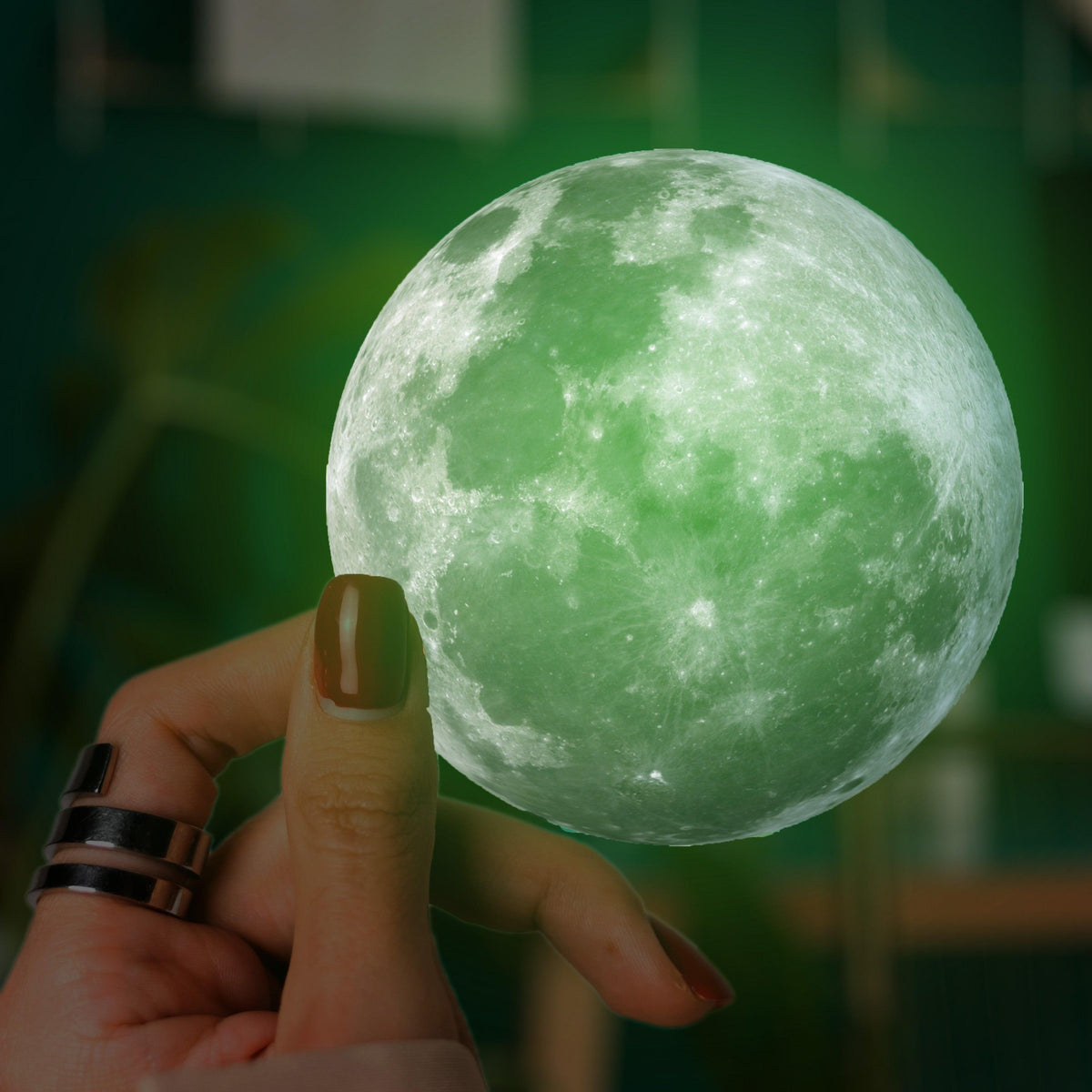 Hand holding a glowing green moon decal.