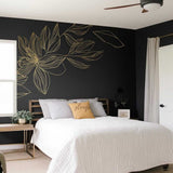 Gold flower wall decal on black wall in modern bedroom, elegant line art design above the bed.