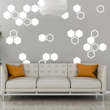 Hexagon glow in the dark wall stickers on a gray wall above a modern sofa with orange cushions.