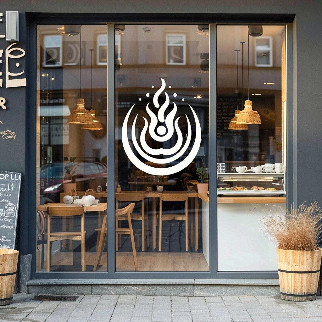 Custom business logo vinyl decal on cafe window with modern decor and lighting.