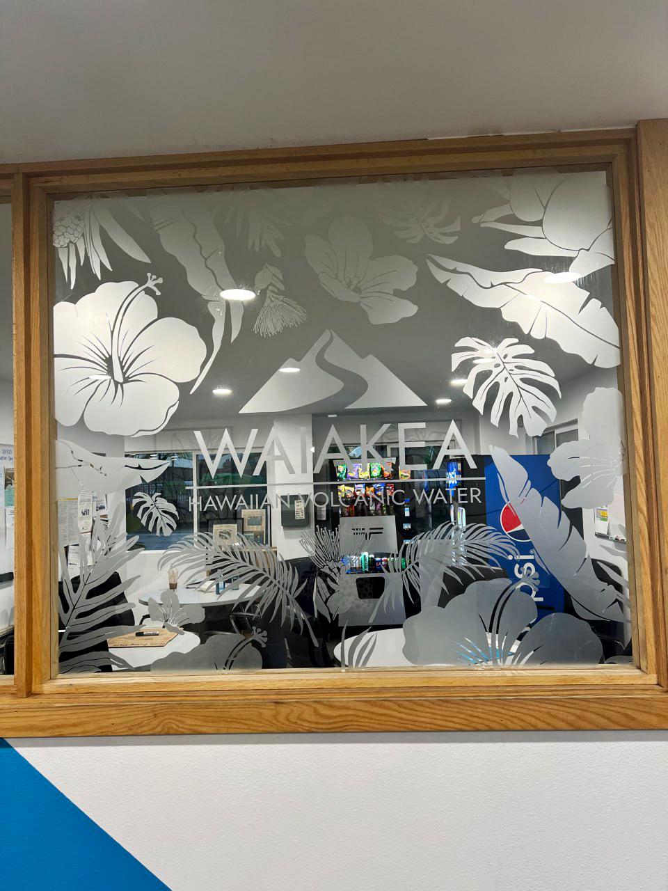 Custom etched mirror decal with floral design for office window showcasing 'Waiakea Hawaii Volcanic Water'.