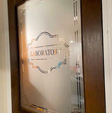 Elegant frosted mirror decal on a laboratory door, featuring a decorative border and the word 'LABORATORY'.