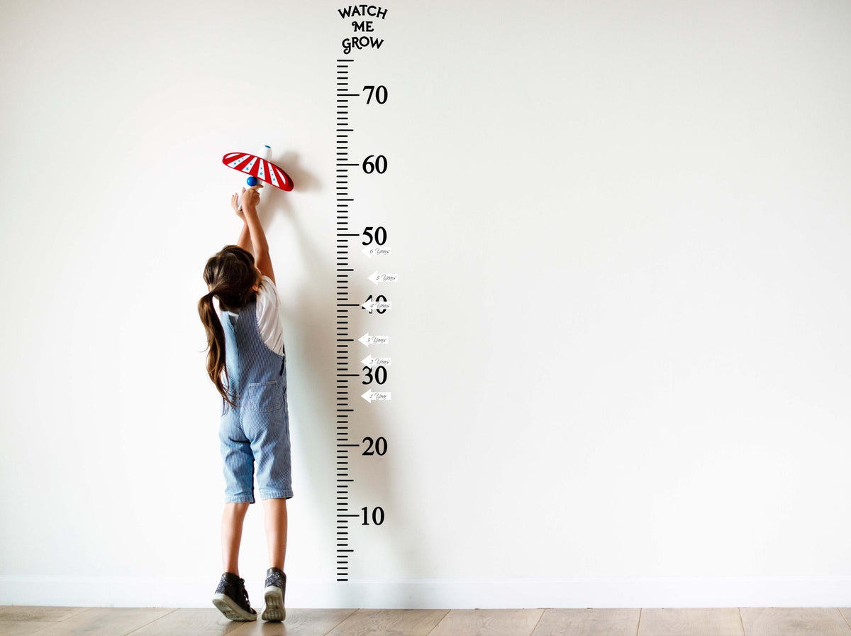 Child measuring height on a wall growth chart decal, stylish way to track growth milestones up to 70 inches.
