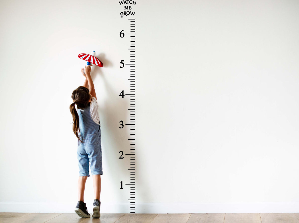 Child reaching for a height marker on a Growth Chart Ruler Vinyl Wall Decal measuring up to 6 feet.