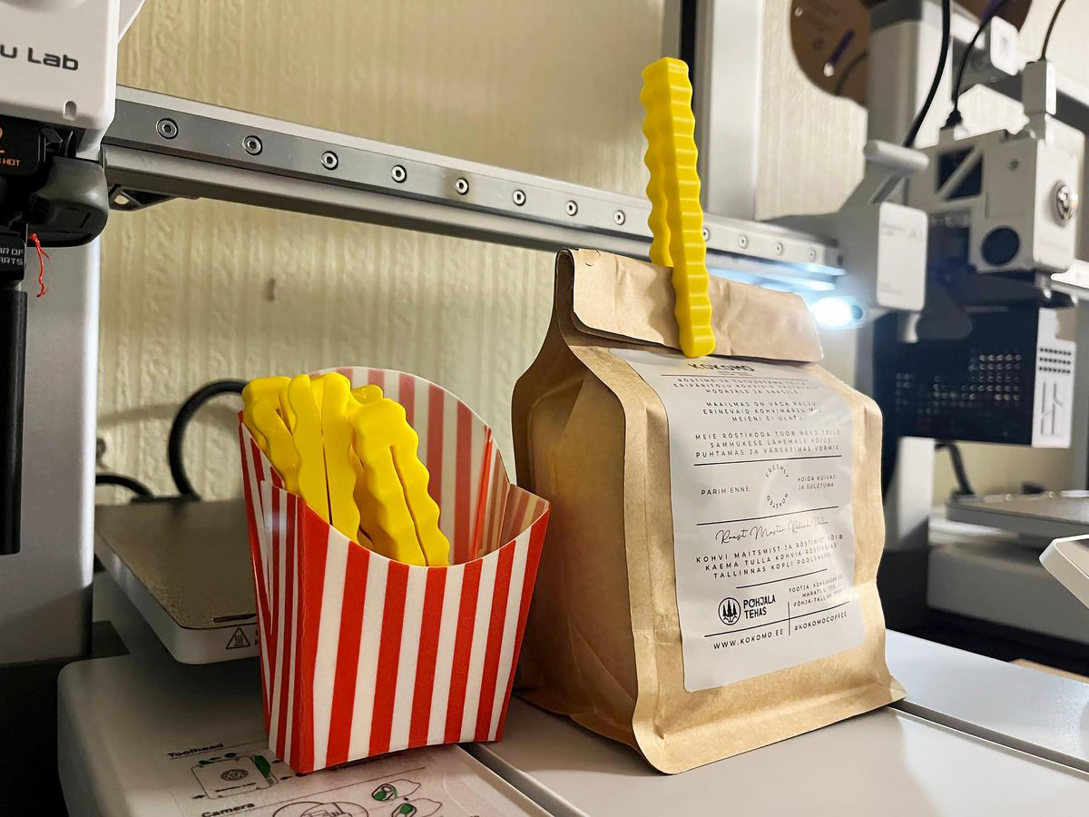3D printed French fry snack sealers in a striped container beside a sealed bag, adding fun to pantry organization.