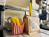 3D printed French fry snack sealers in a striped container beside a sealed bag, adding fun to pantry organization.