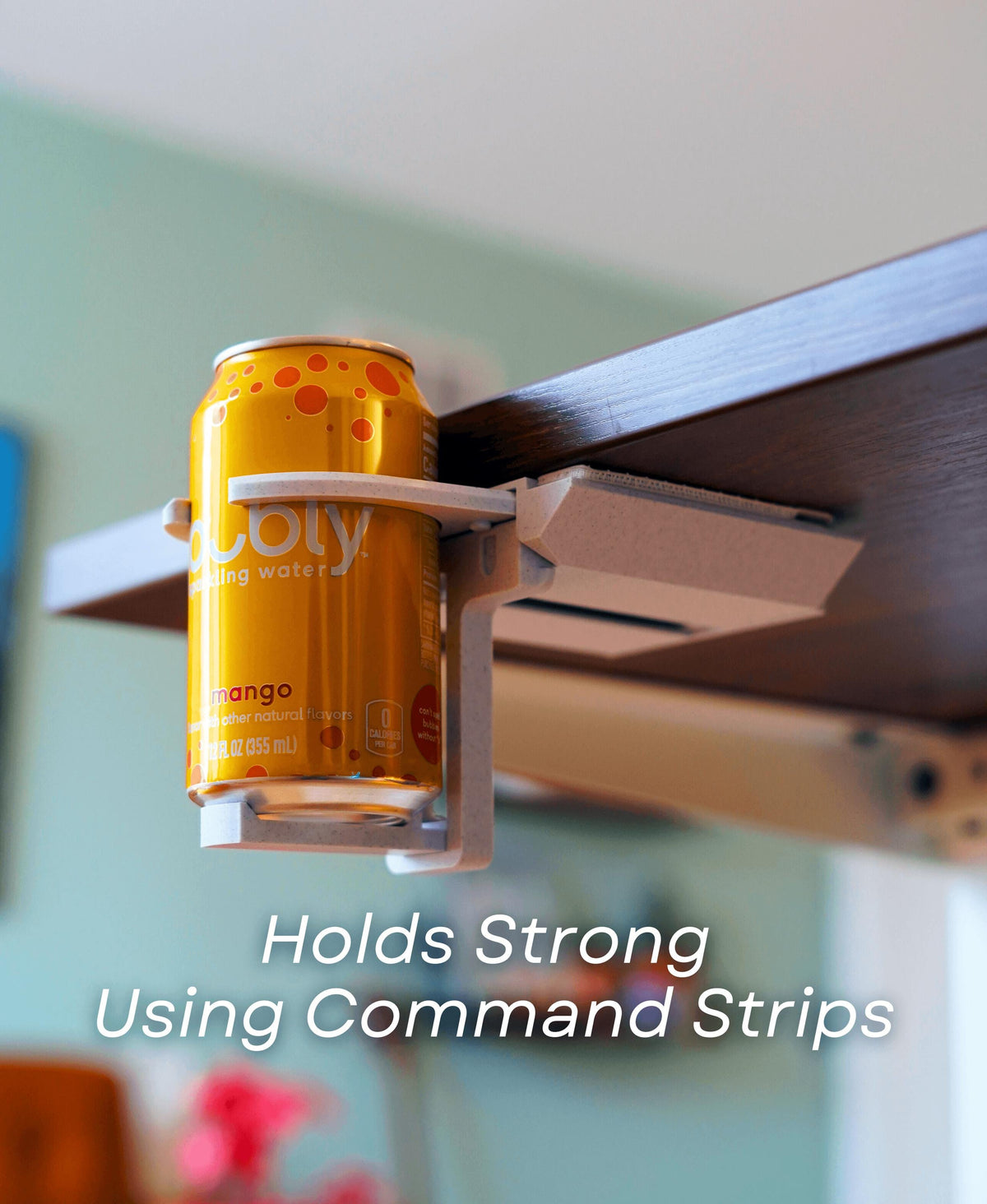 Fold-out under desk cup holder securely holding a can using Command strips for a tidy workspace.