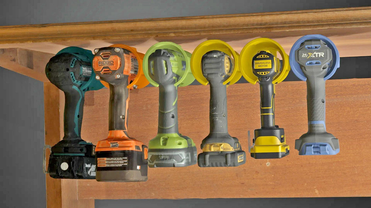 Universal cordless drill holder with multiple drills organized under a shelf for an efficient workshop storage solution.