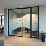 Frosted glass window film with wave design on office partition, ensuring privacy while maintaining natural light.