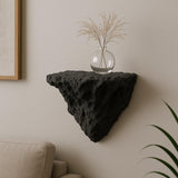A black 3D printed wall-mounted shelf with a rugged, rock-like texture and triangular shape.