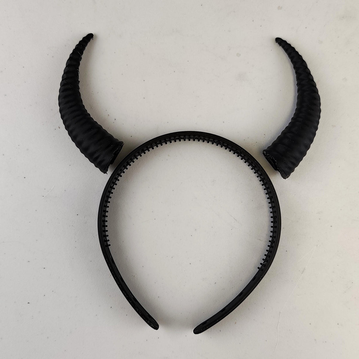 Photo of subtle curved demon horns headband with a coordinated pair of textured curved horns mounted on a lightweight band