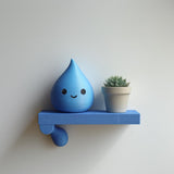 3D printed Water Drop Wall Shelf with small water drop character and a plant pot on a slim rectangular ledge