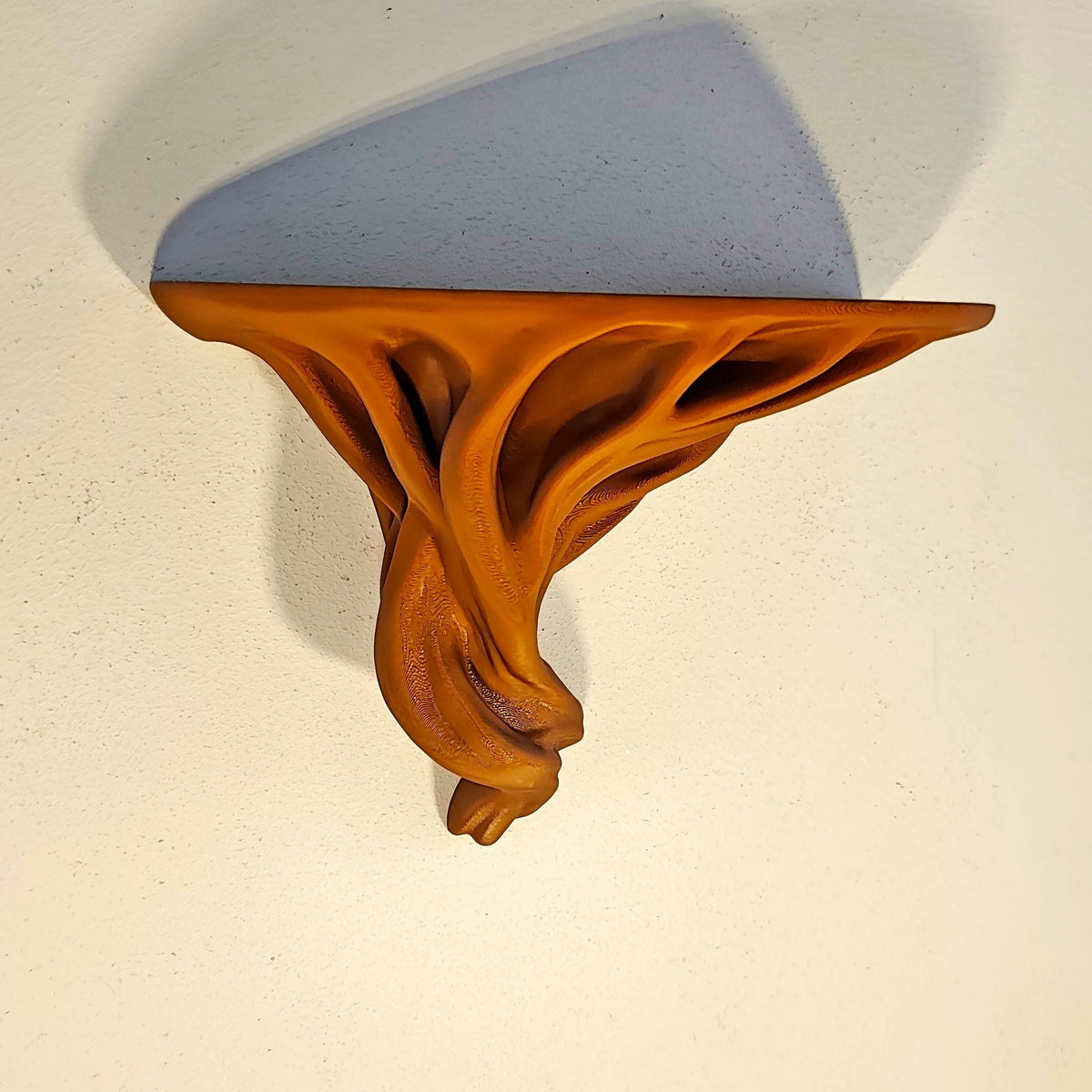3D printed tree root wall shelf with twisting organic supports beneath a compact ledge