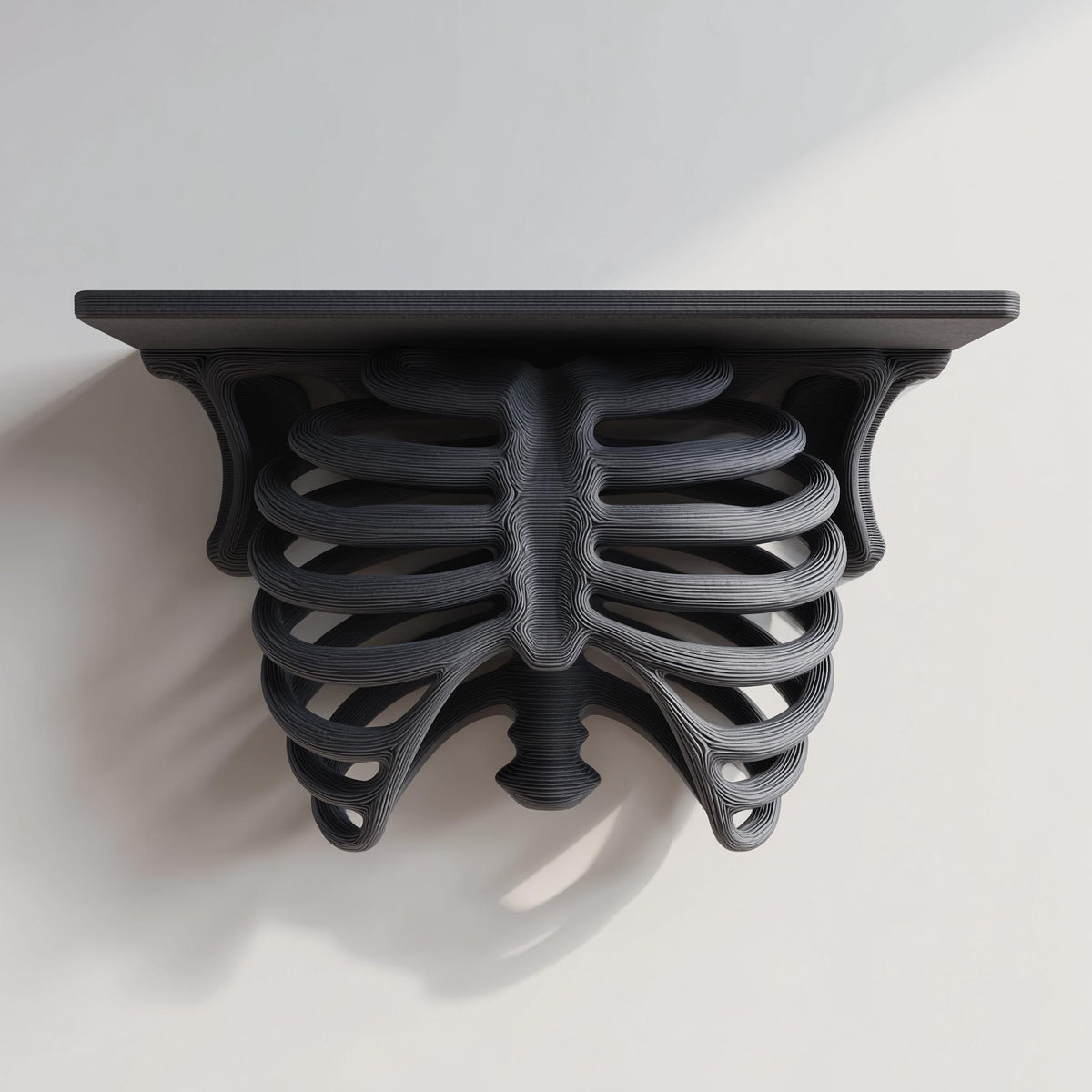 3D printed matte black PLA wall shelf with a realistic ribcage and spine forming the support under a flat rectangular ledge.