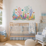 Underwater coral reef wall sticker above a white baby crib in a pale coastal nursery.