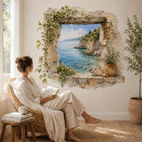 Woman reading in an armchair beside a faux stone window wall decal overlooking a blue sea.