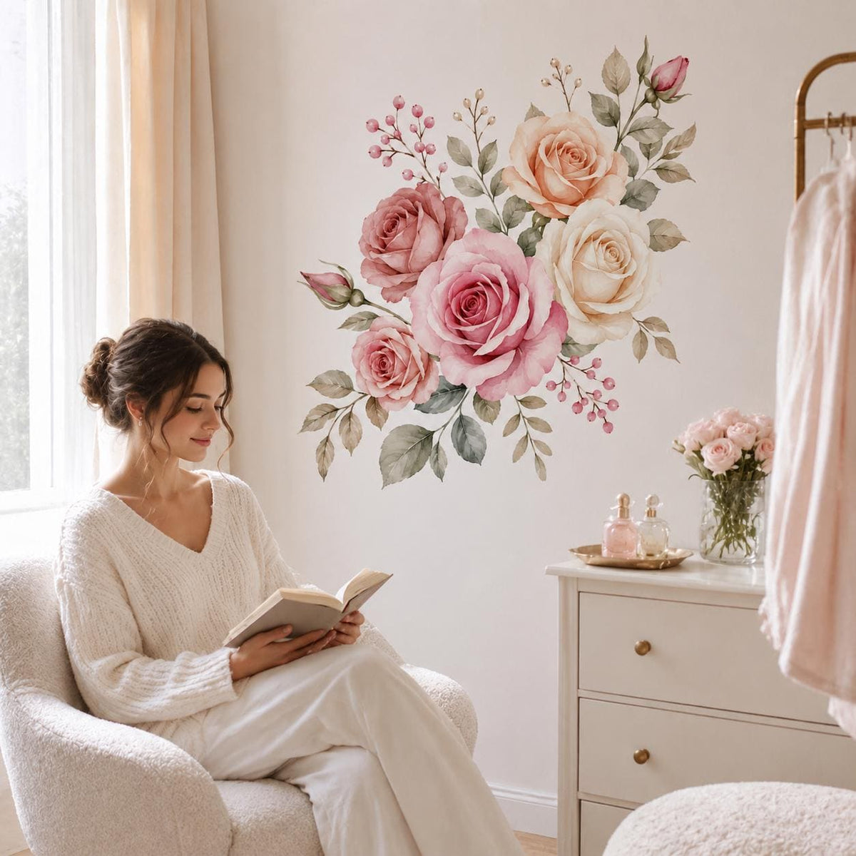Woman reading by a dresser below a pink rose bouquet wall sticker.