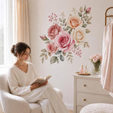 Woman reading by a dresser below a pink rose bouquet wall sticker.