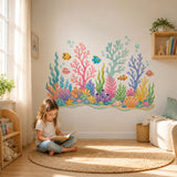 Young girl reading beneath a colorful underwater reef wall decal in a bright room.